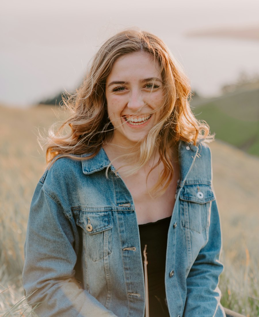 A woman smiling outdoors in warm light
